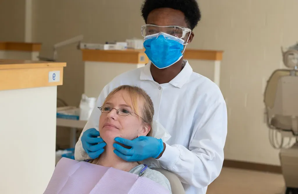 A U N E dental student does a palpation exam on a patient's jaw